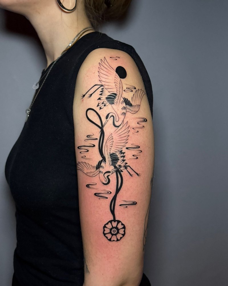 Kraniche in kräftigem Linework mit schwarzen Flächen am Oberarm